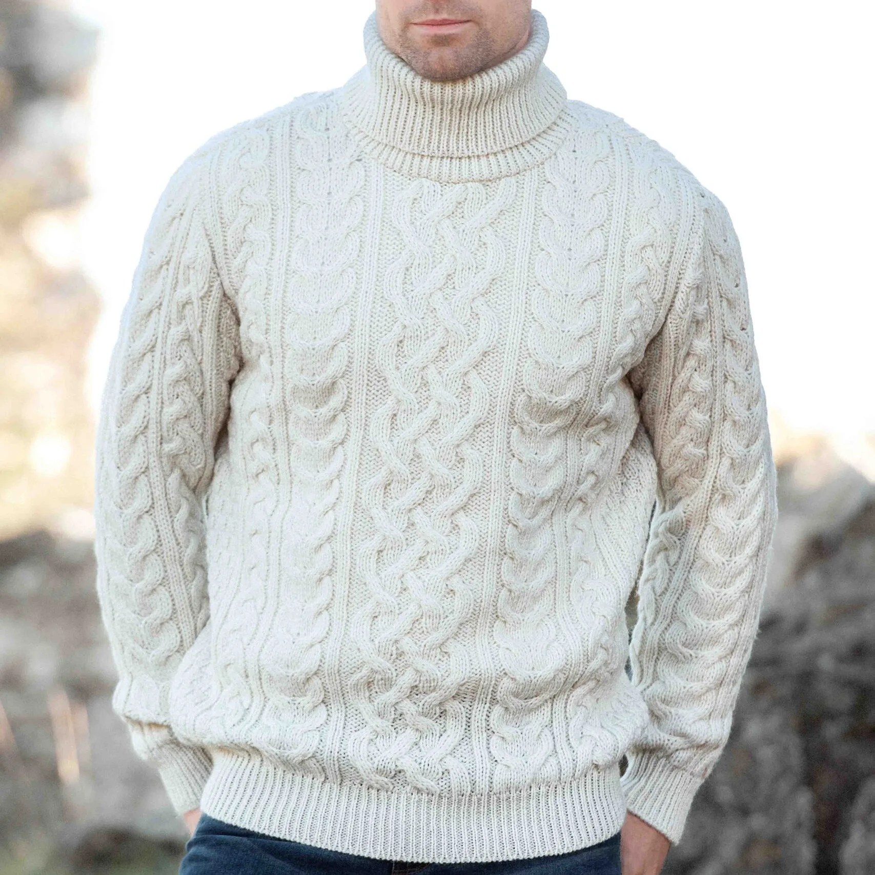 Cream-colored cable knit turtleneck sweater worn by a person outdoors.