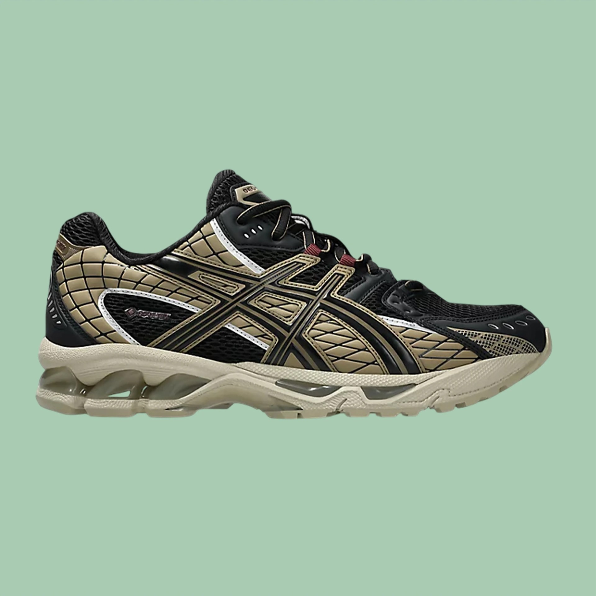 Black and beige Asics running shoe with mesh and synthetic upper and cushioned sole on green background.