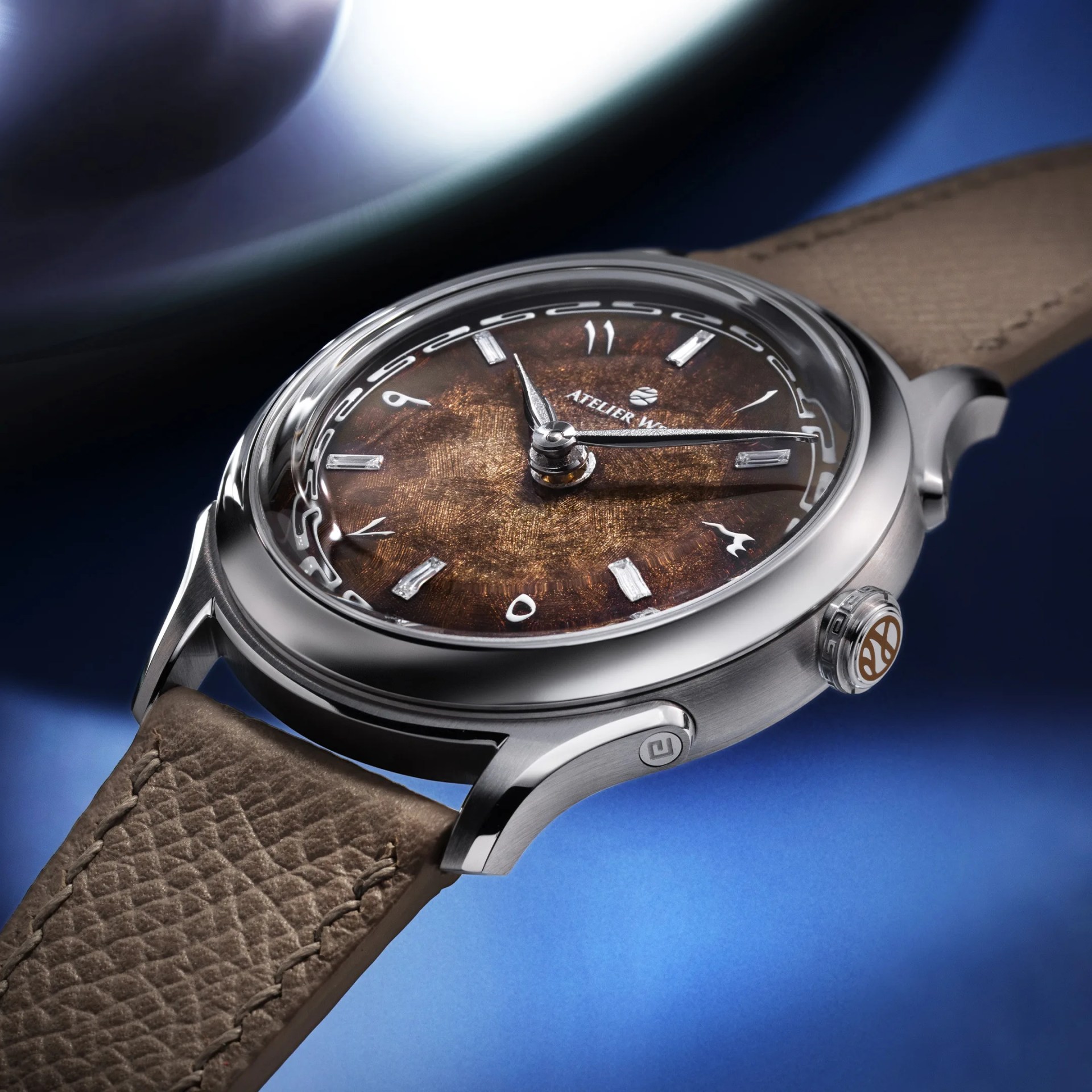 Round wristwatch with a textured brown dial, silver case, and taupe leather strap on a blue background.