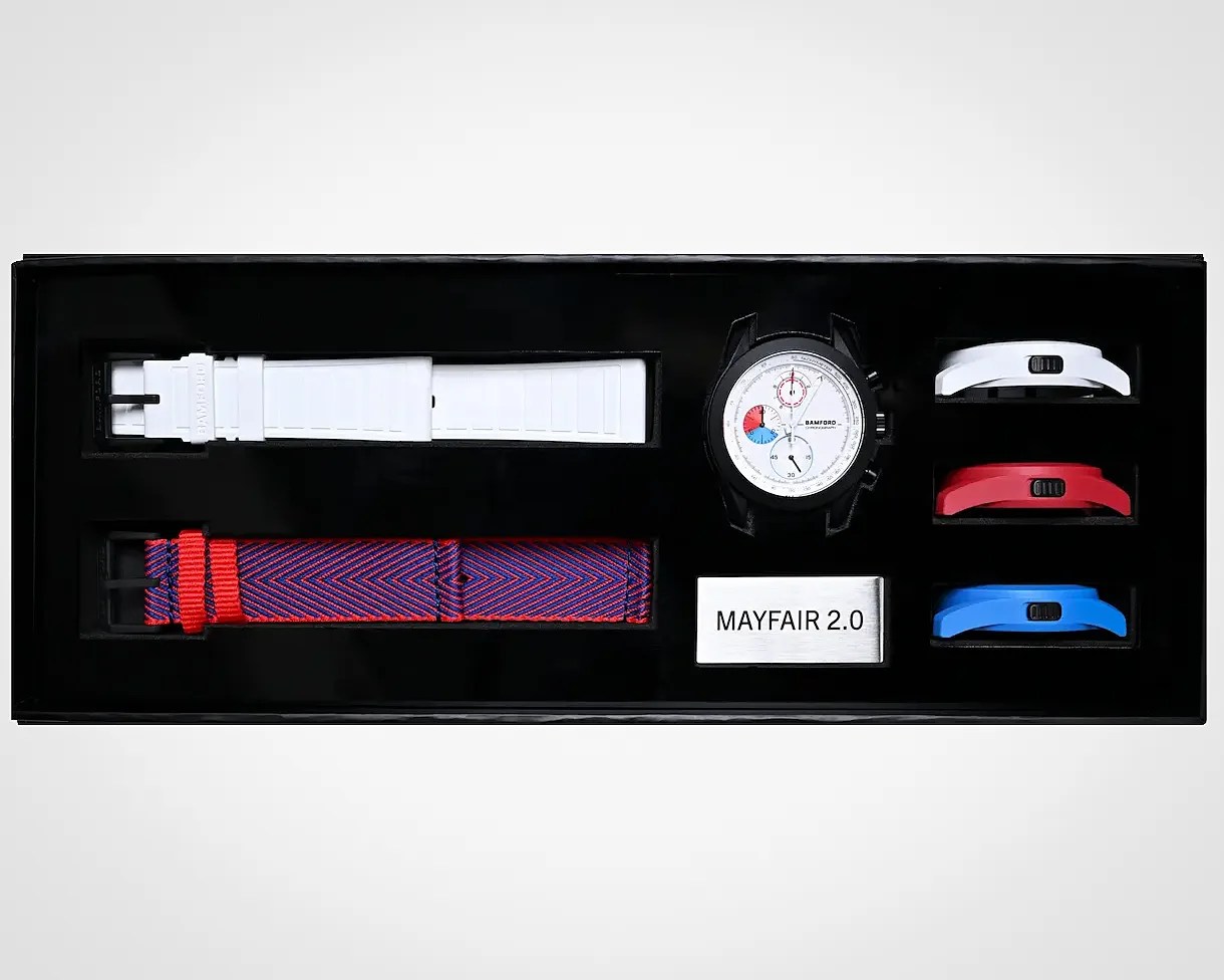 Watch set with a black case, white dial, white and red-blue striped straps, and three additional colored bezels in white, red, and blue.