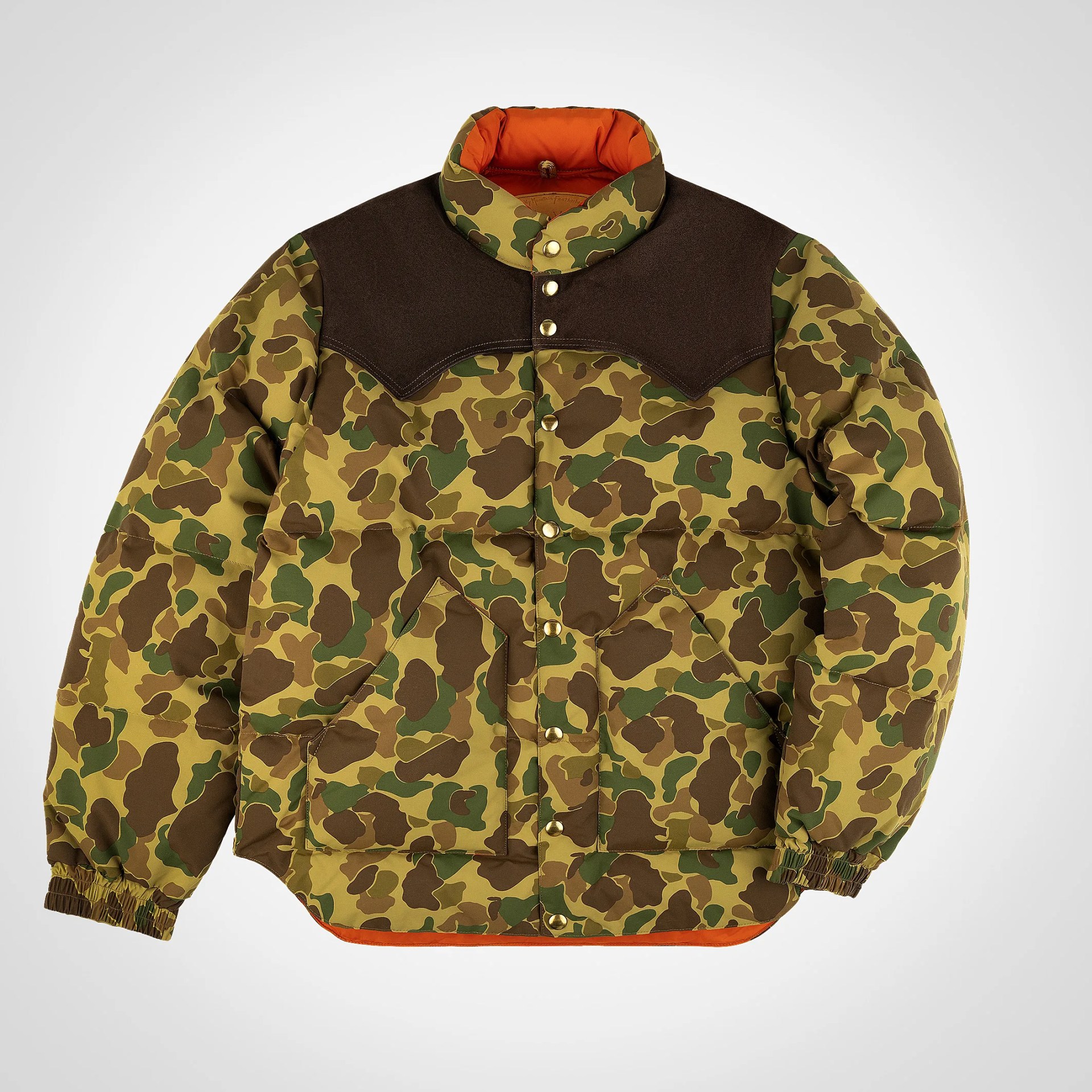 Camouflage puffer jacket with brown shoulder yoke, snap buttons, and orange lining.