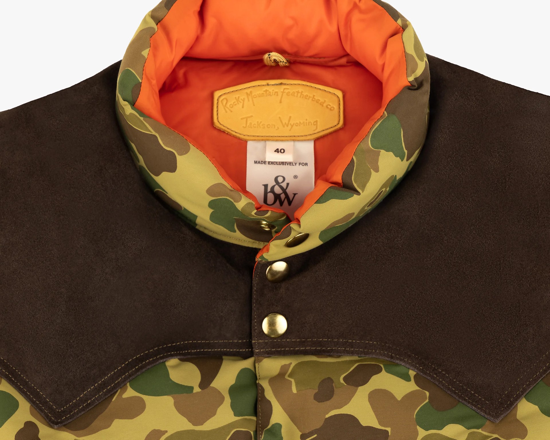 Close-up of a camo jacket collar with orange lining, brown suede yoke, and brass snap buttons.