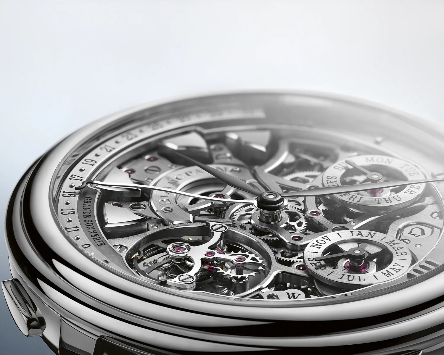 Close-up of a silver skeleton mechanical watch showing intricate gears and calendar dials for days and months.