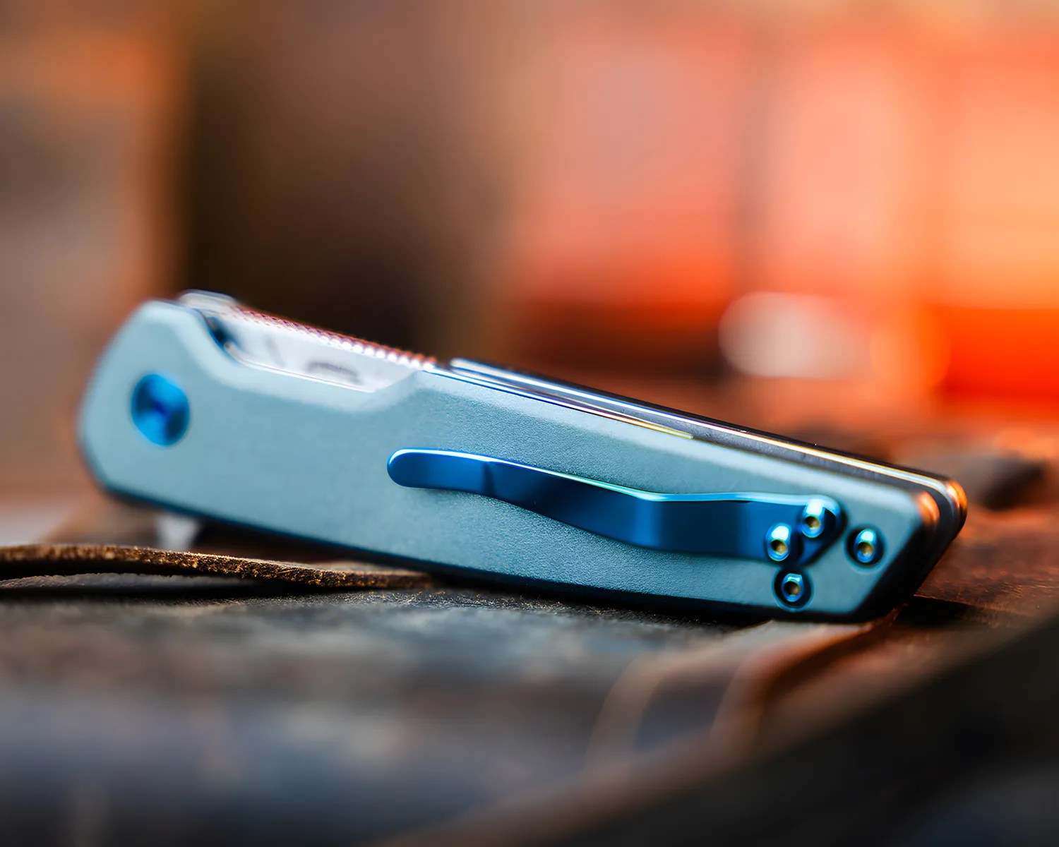 Folded light blue pocket knife with a blue clip resting on a textured surface.