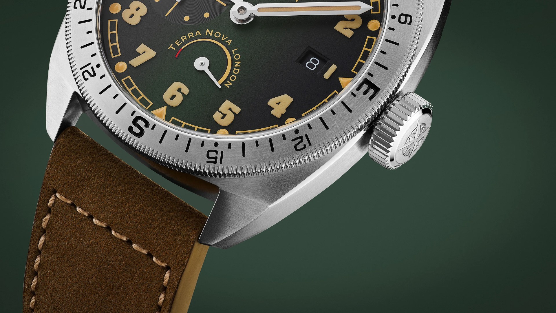Close-up of a stainless steel watch with a green dial, beige numerals, date window, and brown leather strap.