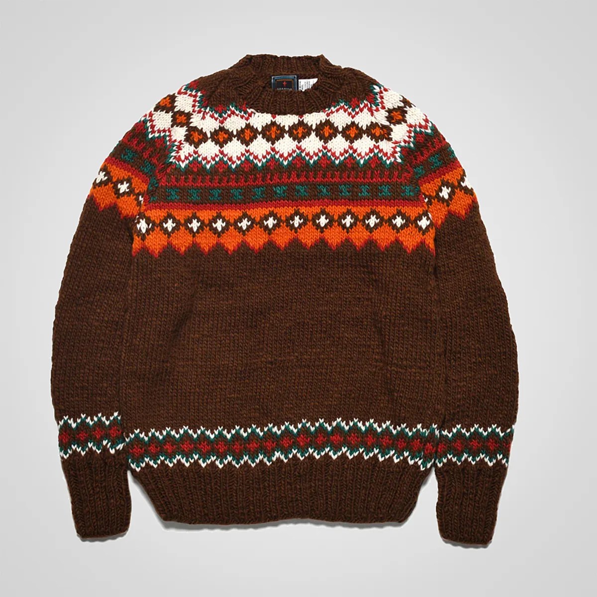 Brown knit sweater with orange, white, green, and red geometric patterns on the chest, sleeves, and hem.