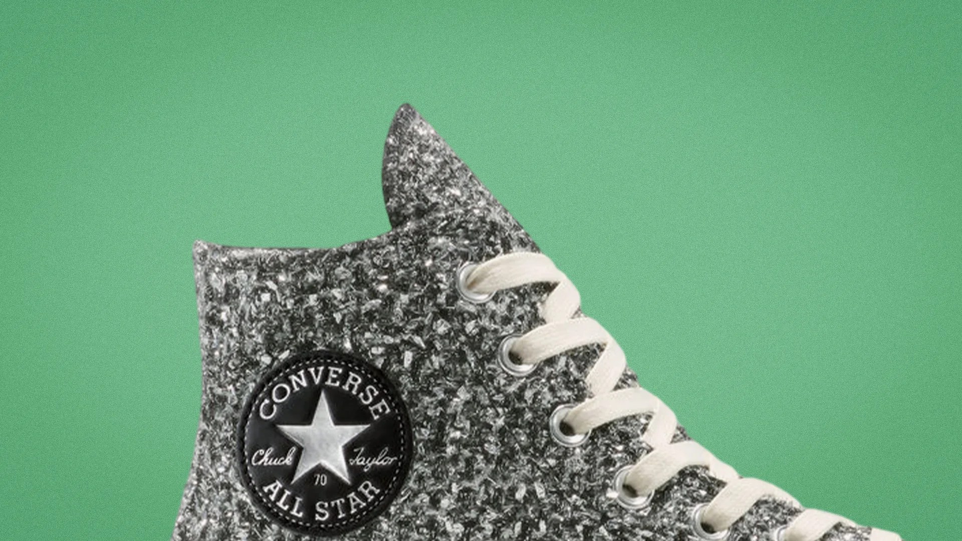 High-top Converse All Star sneaker with a textured black and white knit upper and white laces on a green background.