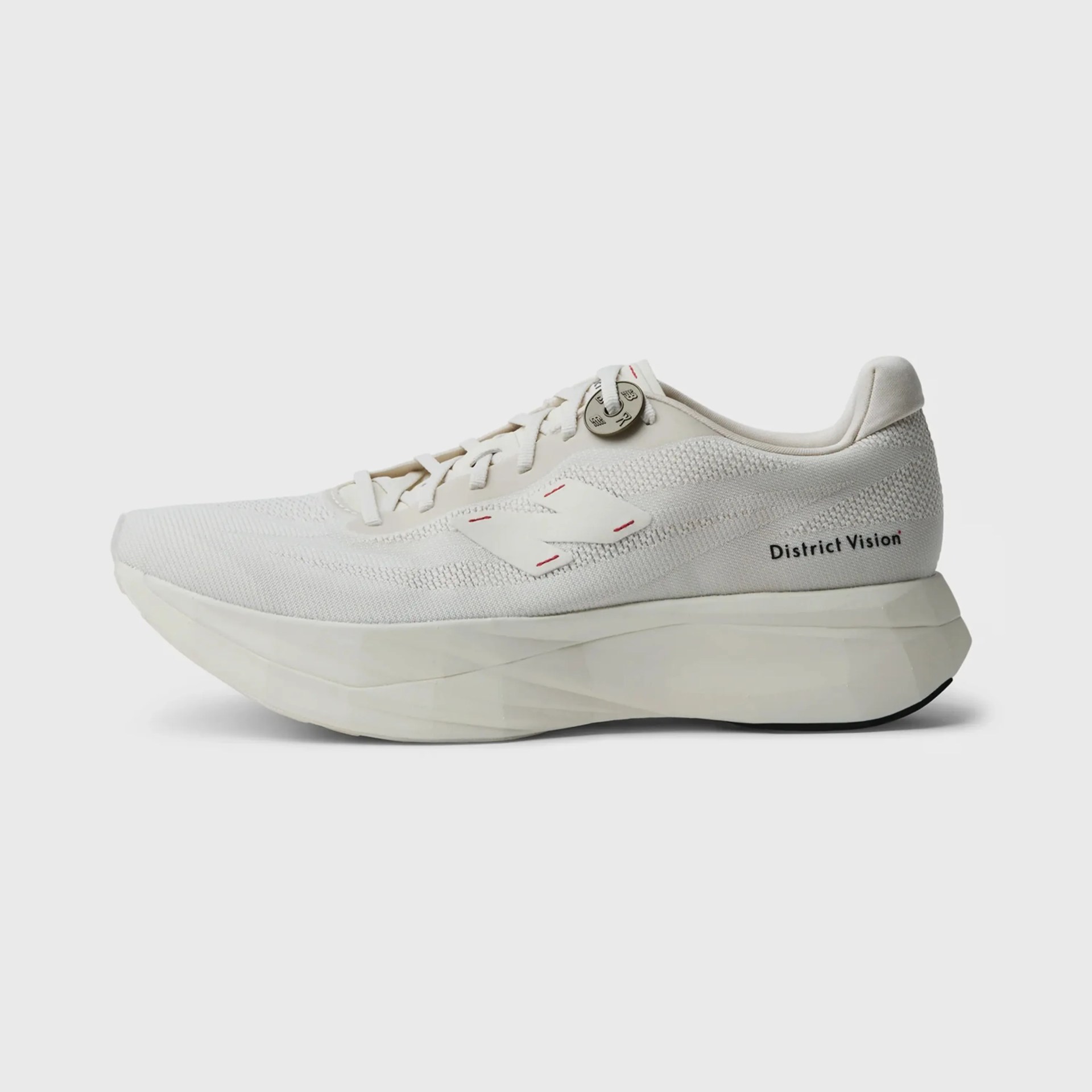 Off-white lightweight running shoe with thick sole and "District Vision" text on the heel.