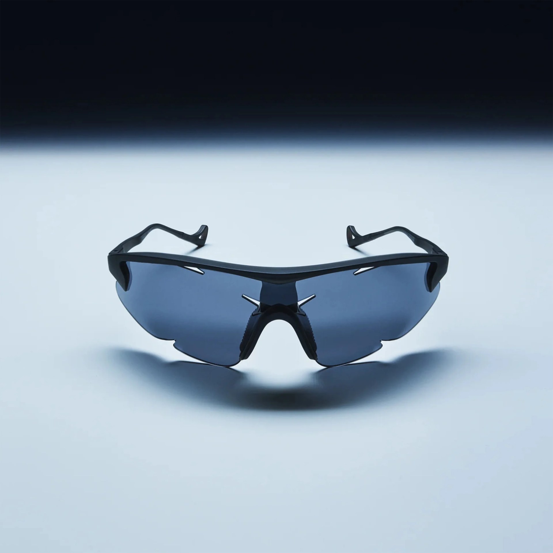 Black sports sunglasses with blue-tinted wraparound lenses on a light surface.
