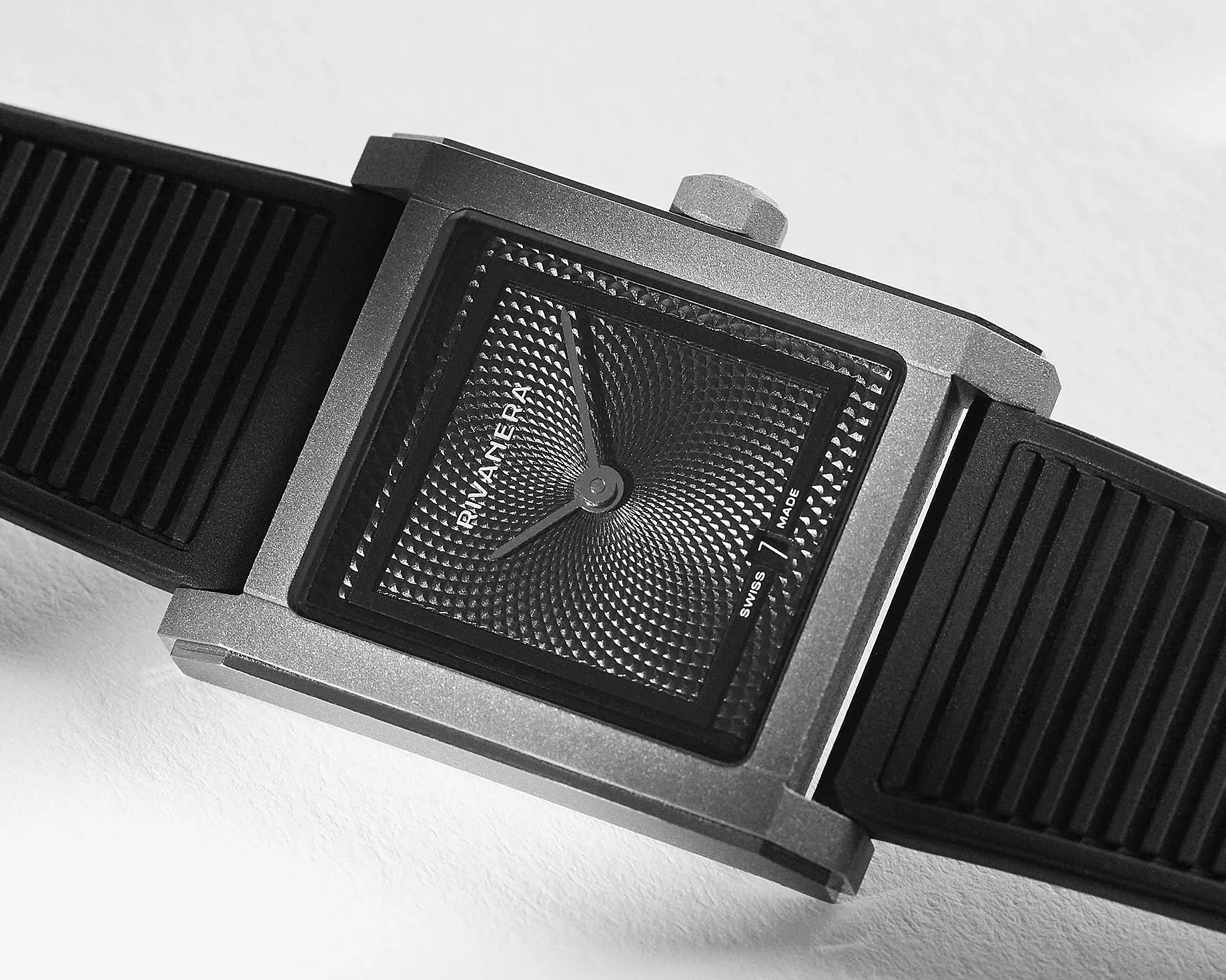Square silver wristwatch with textured black dial and black rubber strap.