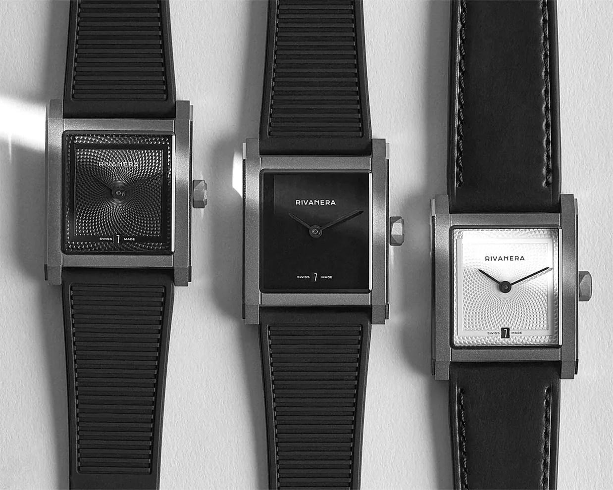 Three square-faced Rivanera wristwatches with black and white dials and black straps on a light surface.