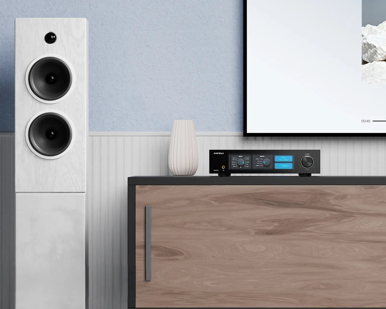 White floor-standing speaker with two large black drivers next to a wooden cabinet holding a black audio receiver and a white vase.