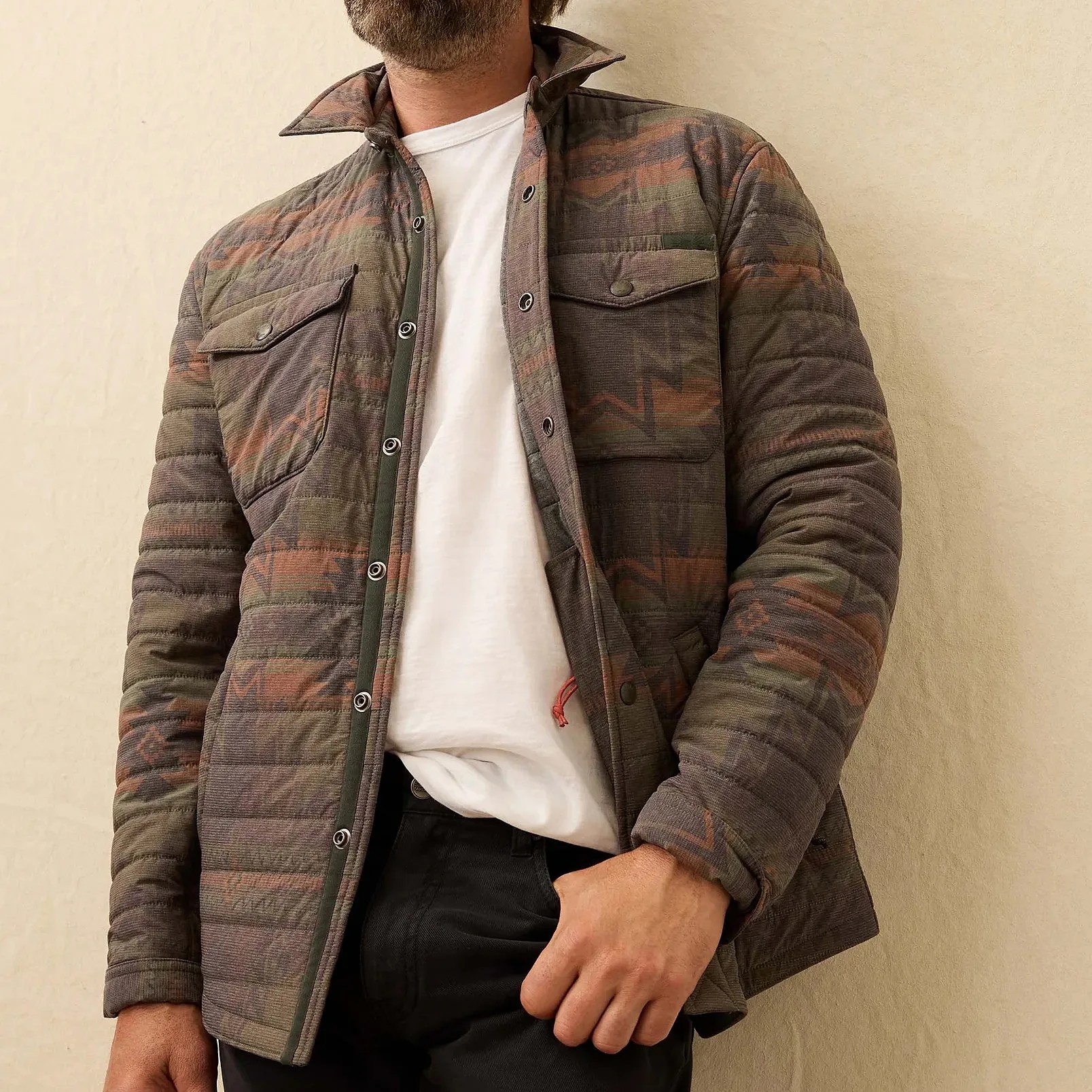 Quilted jacket with snap buttons and chest pockets in muted earth tones with a geometric pattern.