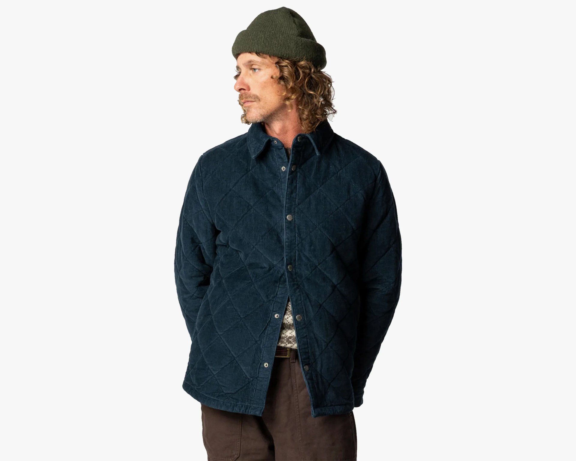 Man wearing a dark blue quilted jacket and olive green knit beanie against a white background.