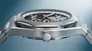 Side view of a silver stainless steel wristwatch with visible mechanical gears and "GP" engraved on the crown.