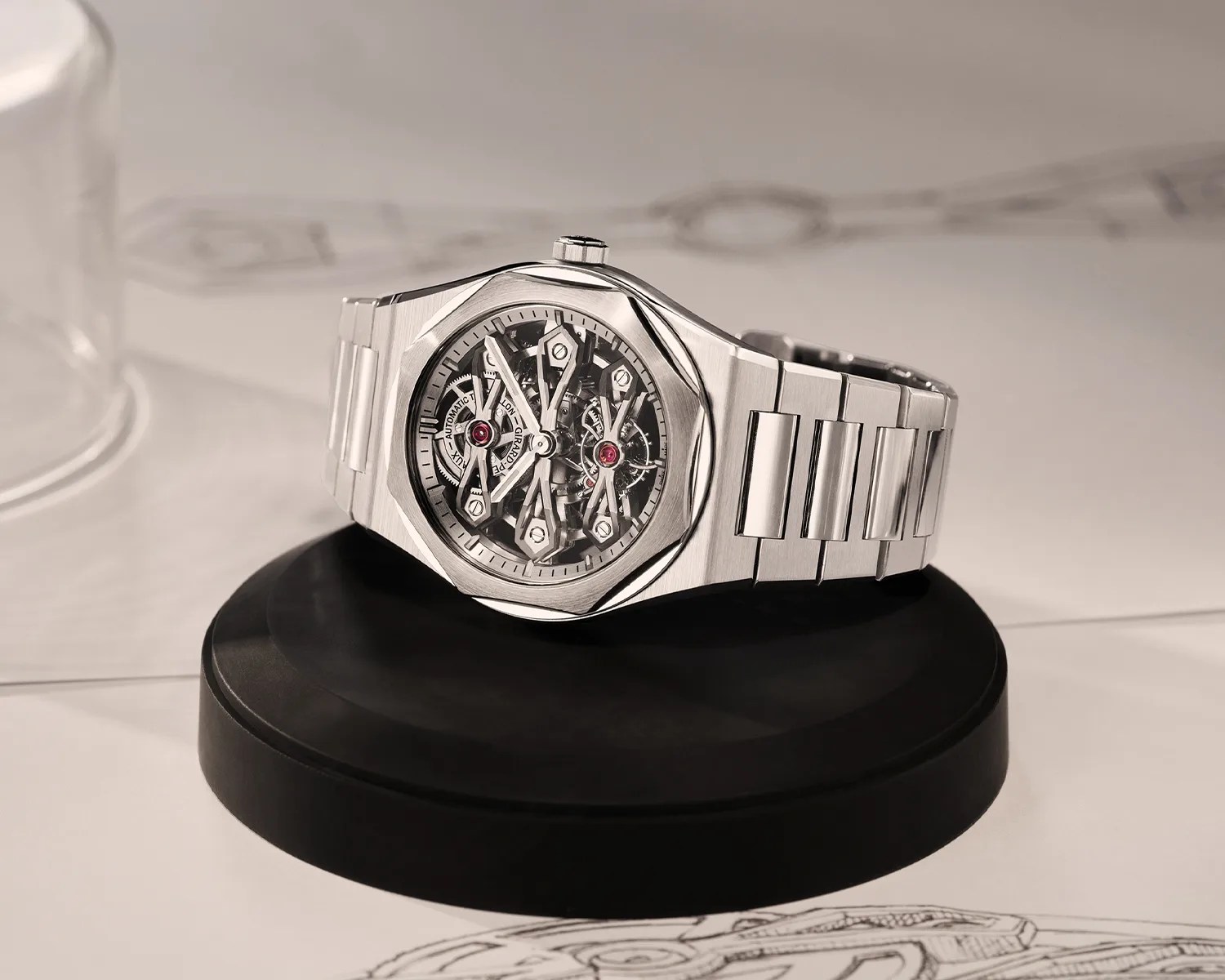 Silver stainless steel skeleton watch with visible gears on a black circular stand.