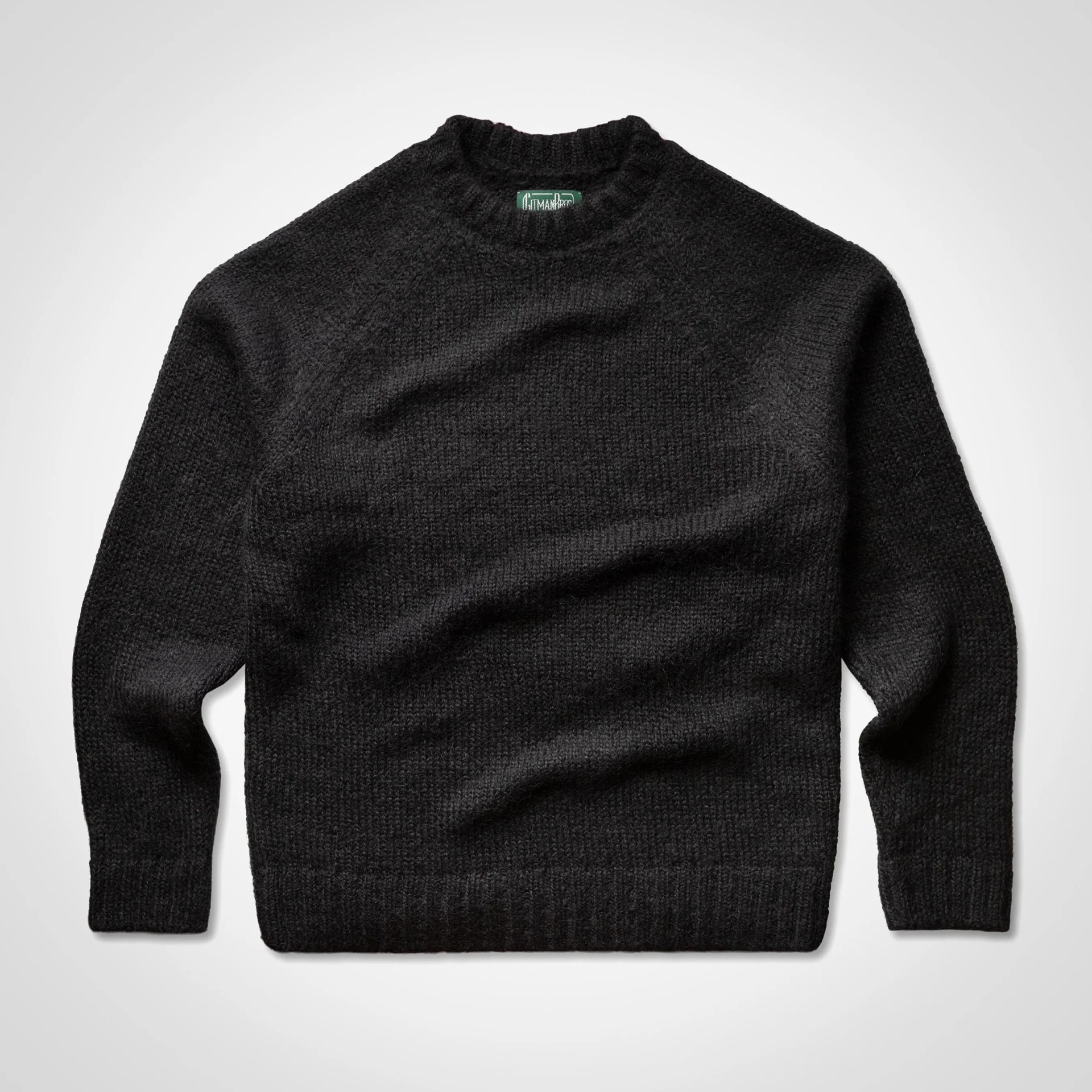 Black knitted crewneck sweater with long sleeves laid flat on a white background.