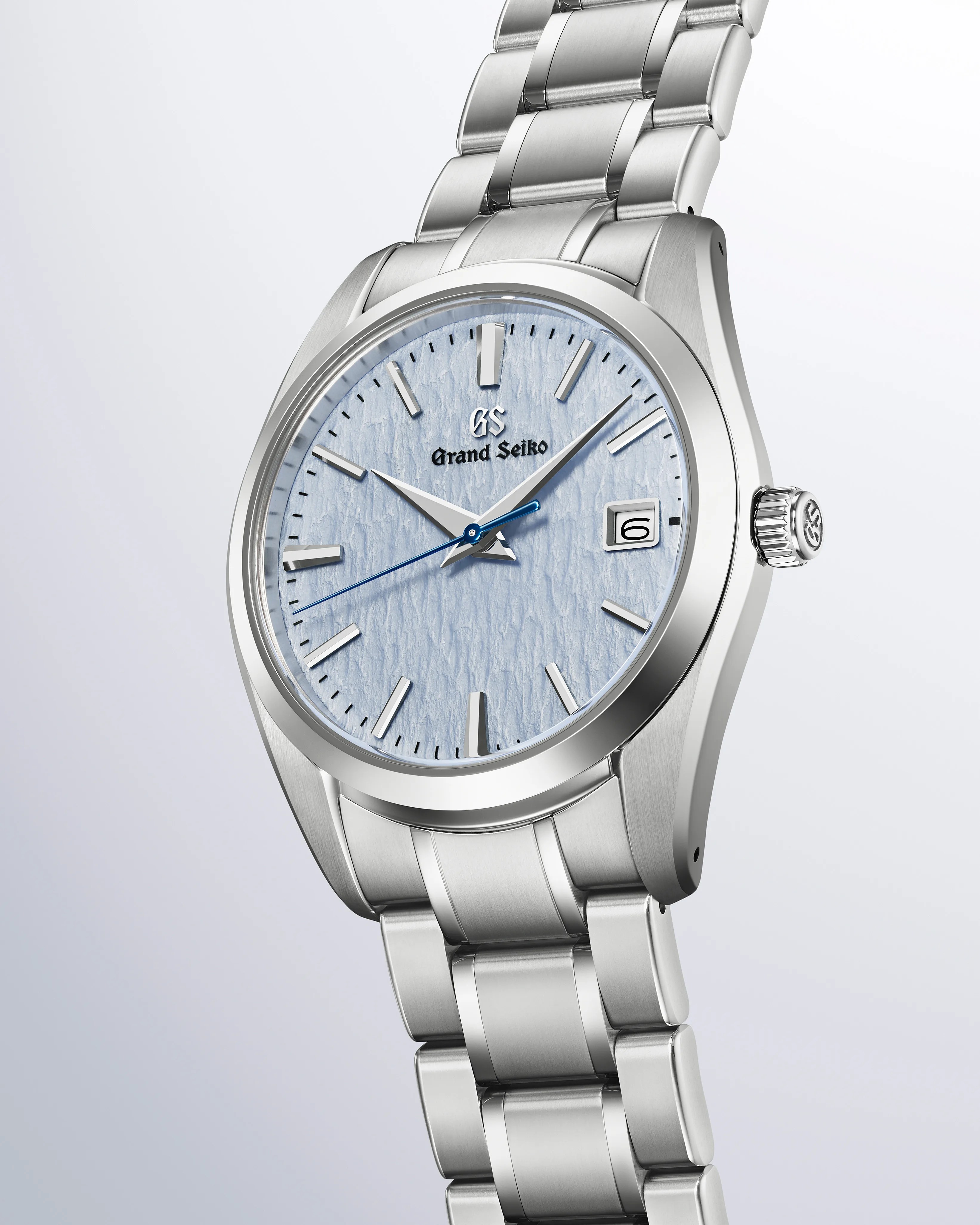 Silver stainless steel Grand Seiko wristwatch with textured light blue dial and blue second hand.