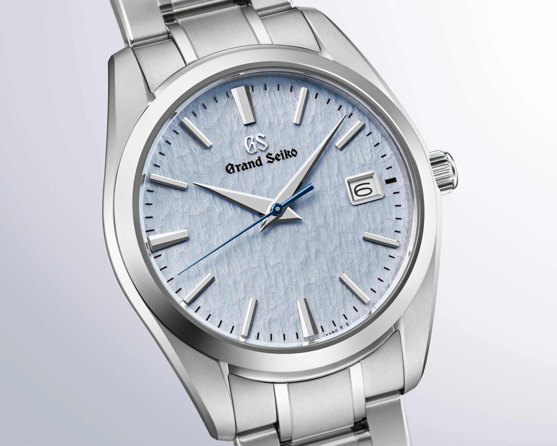 Silver stainless steel Grand Seiko wristwatch with textured light blue dial and date window at 3 o'clock.