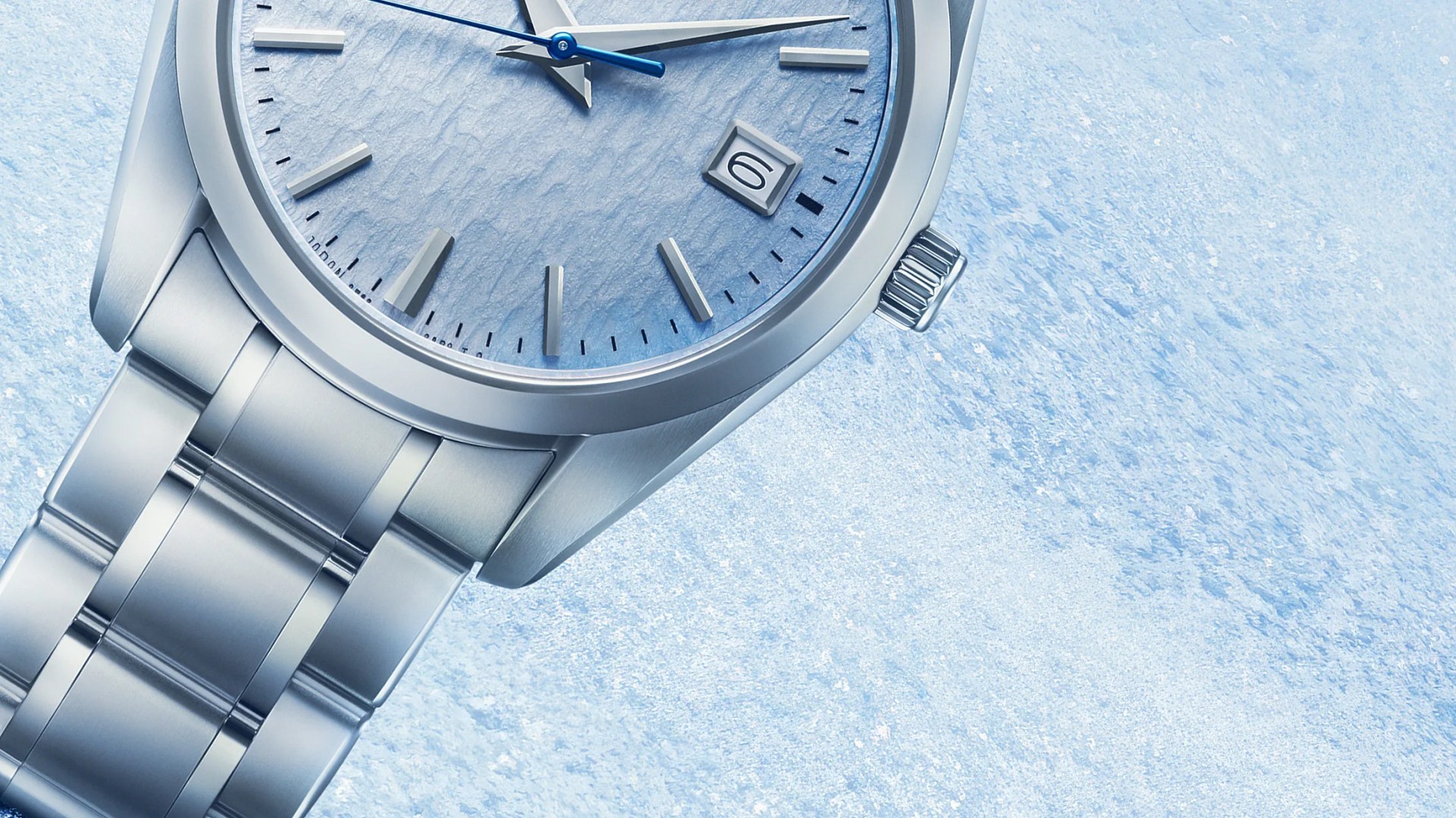 Silver metal wristwatch with a textured light blue dial and blue second hand on a matching blue textured background.