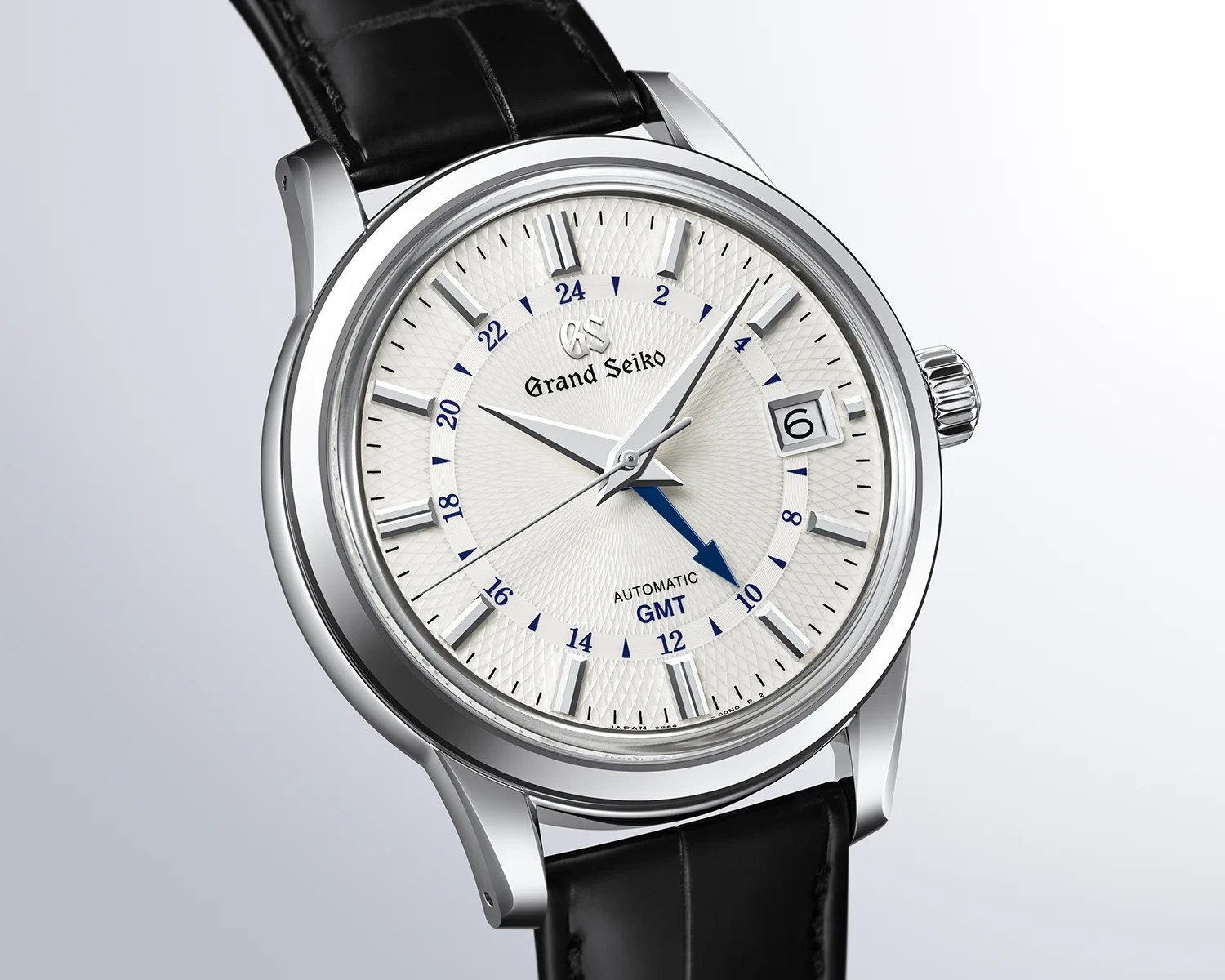 Silver Grand Seiko wristwatch with textured white dial, black leather strap, and blue GMT hand.