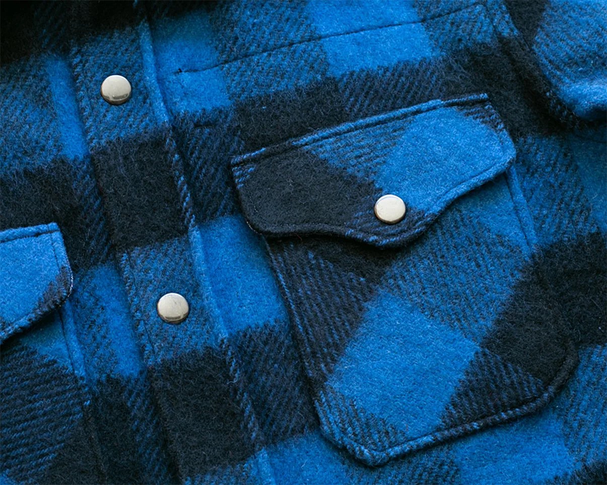 Close-up of a blue and black plaid wool shirt pocket with a silver snap button.