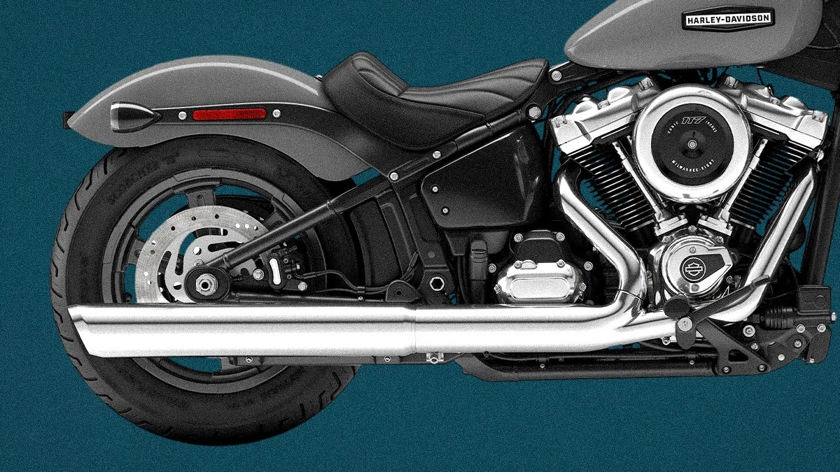 Close-up of the rear half of a gray Harley-Davidson motorcycle showing the seat, exhaust pipes, and engine.