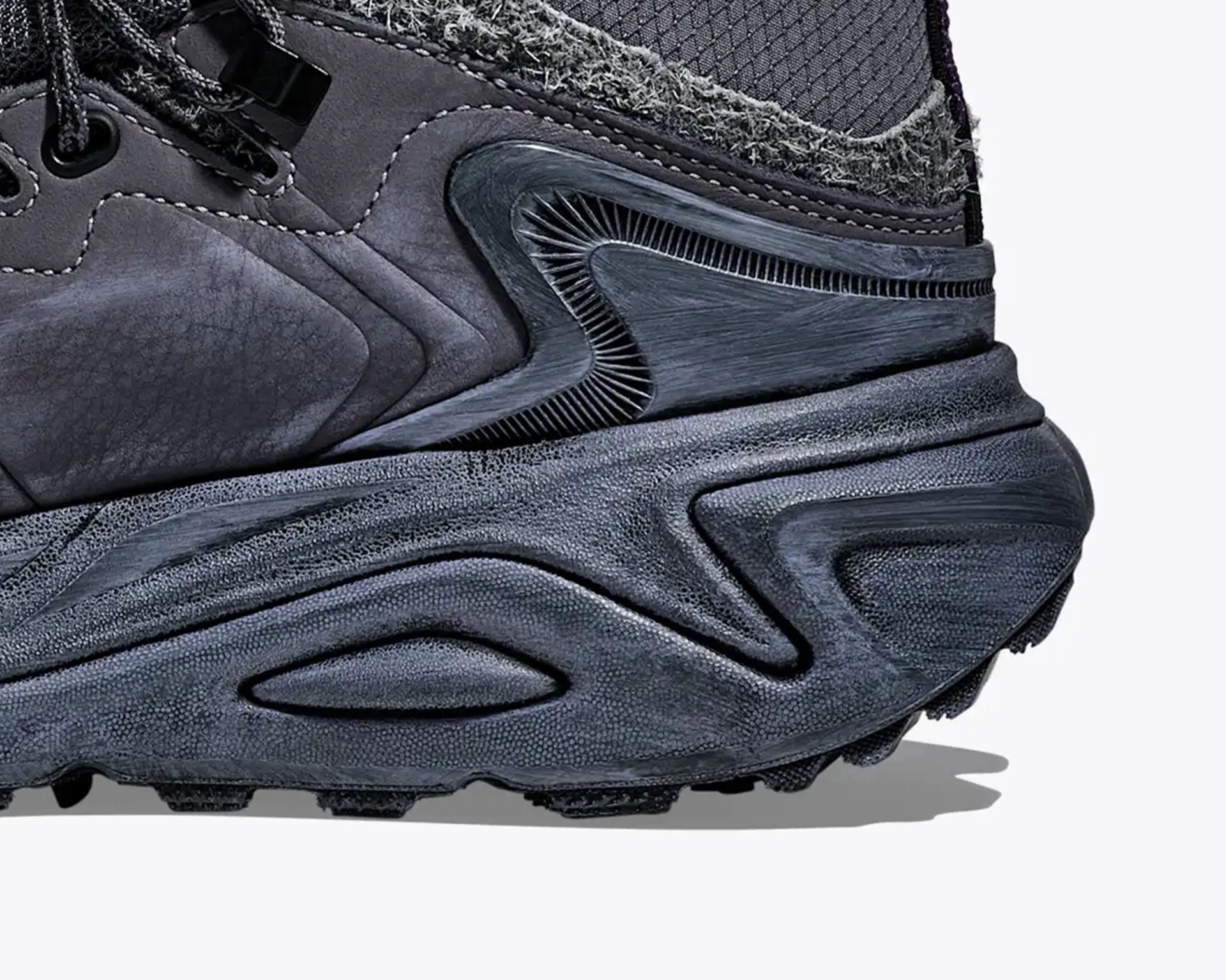 Close-up of the heel and midsole of a dark gray sneaker with textured and layered materials.