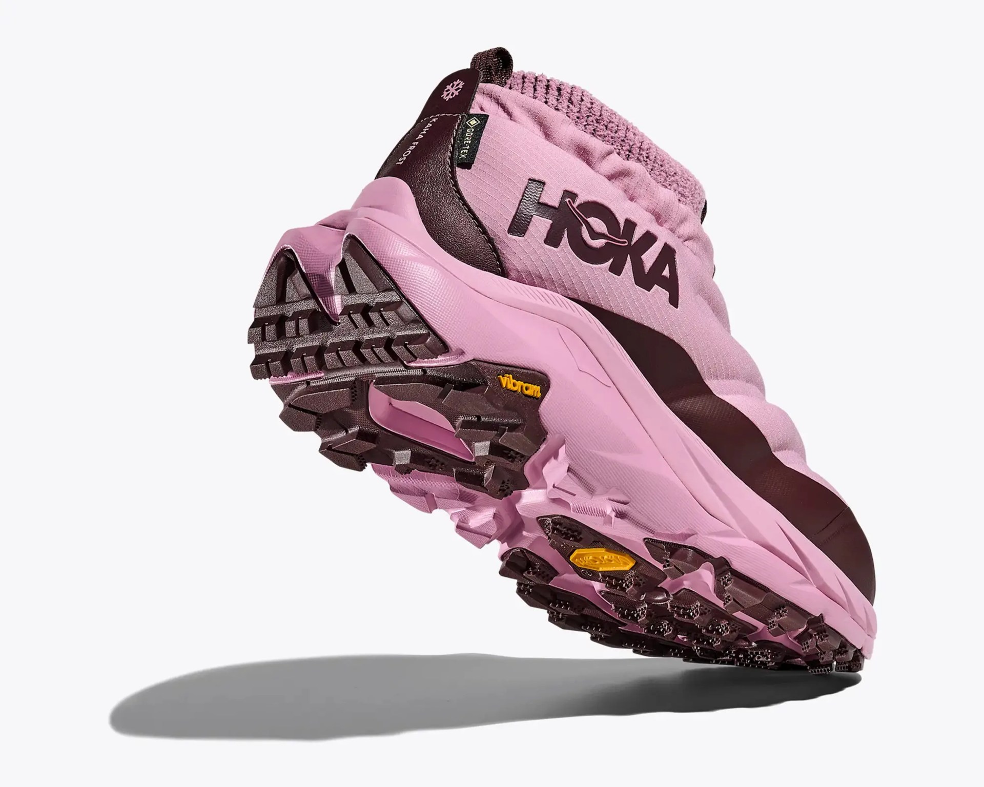 Pink and dark brown HOKA hiking shoe with Vibram sole and Gore-Tex label angled upward.