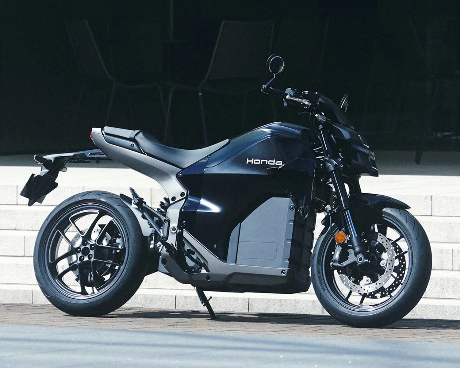 Black Honda electric motorcycle with sleek body and disc brakes parked on pavement near steps.