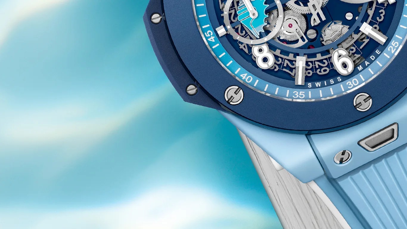 Close-up of a blue wristwatch with a detailed mechanical dial and light blue rubber strap.