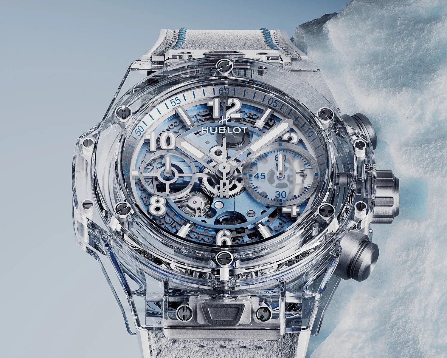 Transparent Hublot wristwatch with visible blue gears and white numerals on a light gray strap.