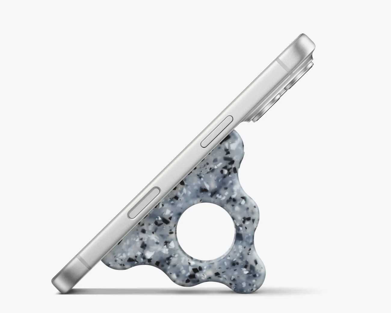 Silver smartphone propped at an angle by a blue-gray speckled triangular stand with a circular hole in the center.