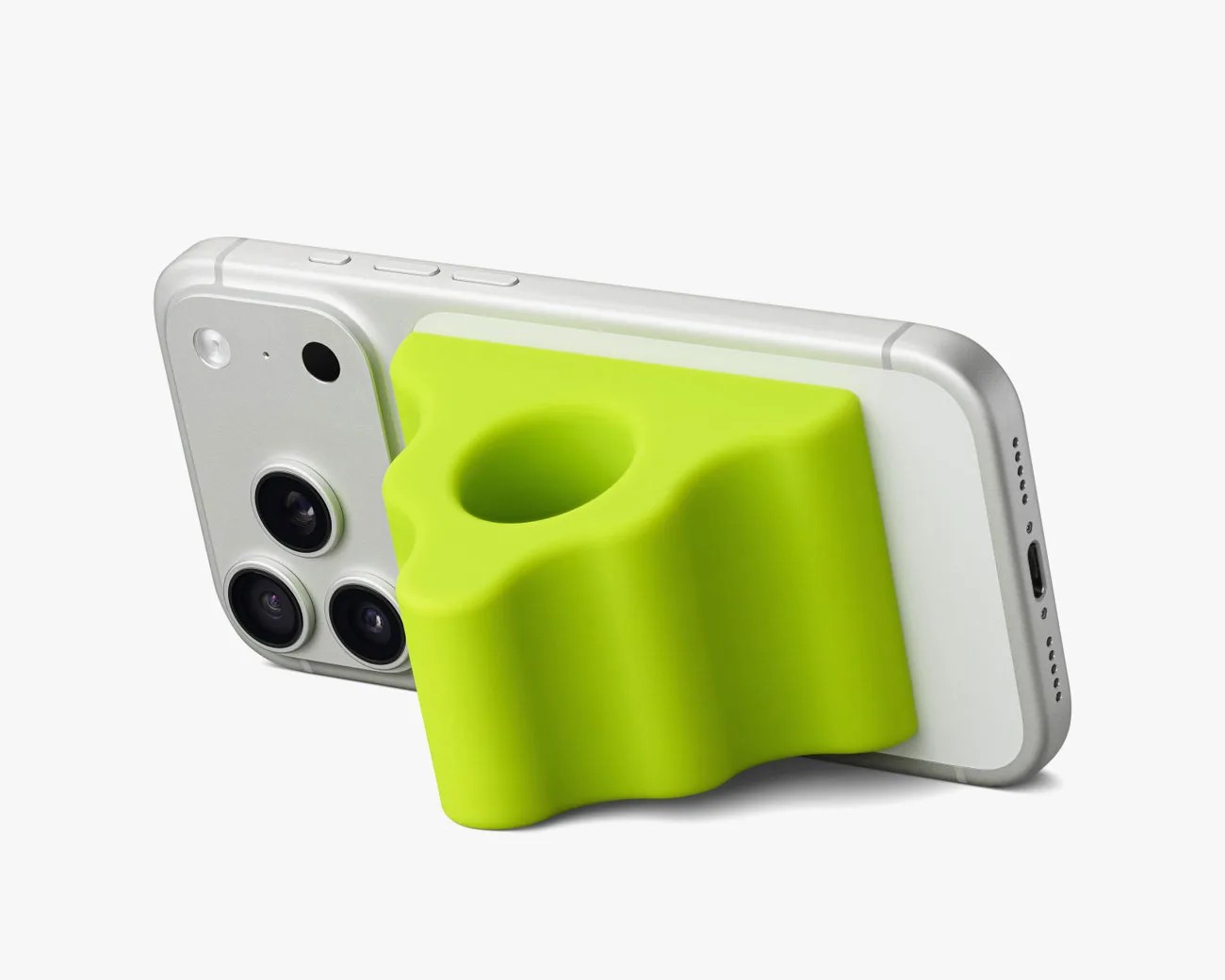 White smartphone with triple camera lenses and a bright green silicone grip stand attached to the back.