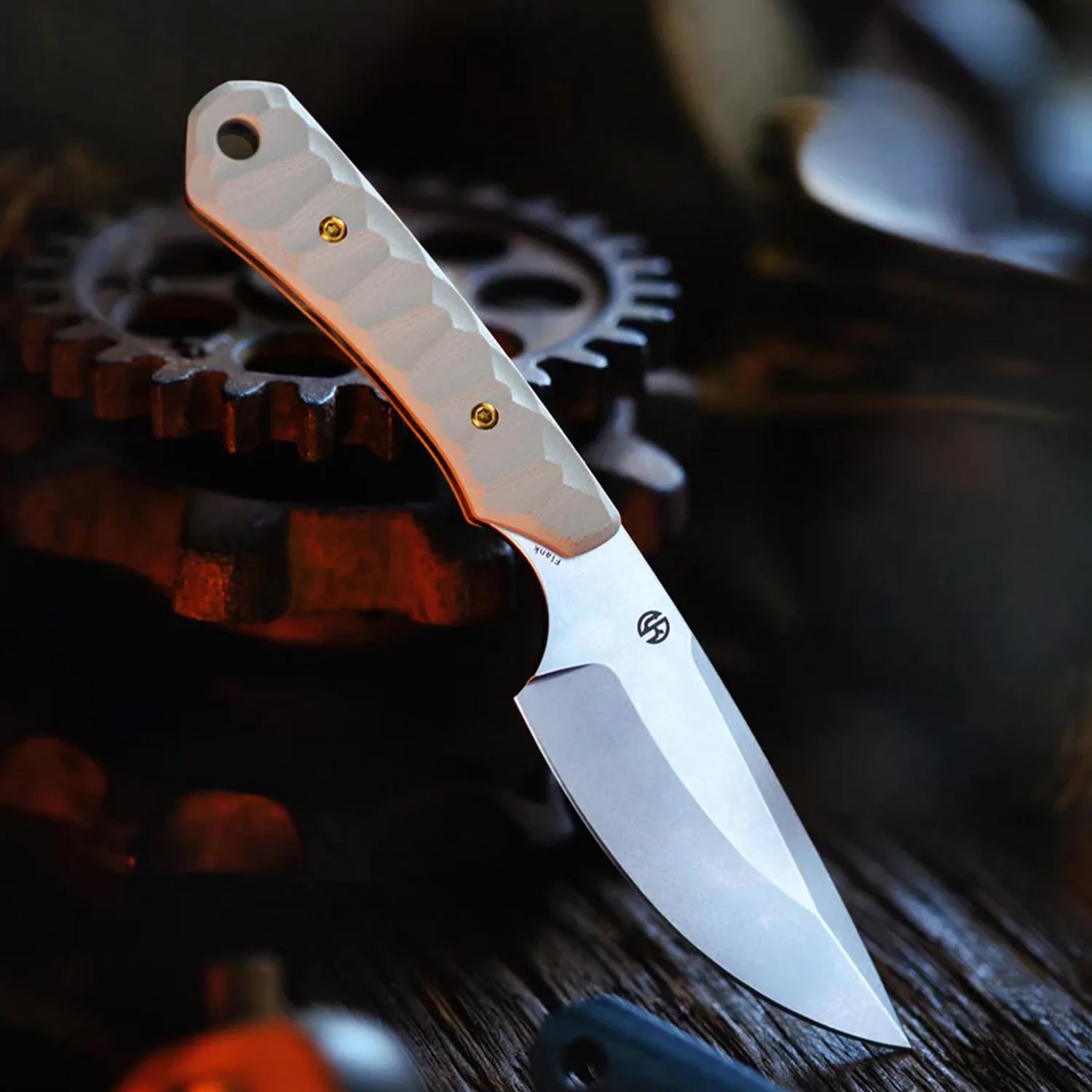 Fixed-blade knife with a textured white handle and a stonewashed blade resting on metal gears.