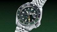 Silver Seiko automatic GMT wristwatch with black and green bezel and luminous markers on a metal bracelet.