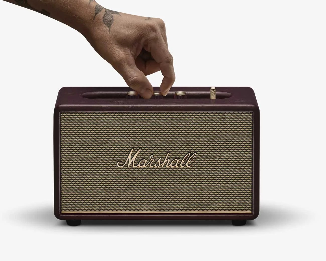 Hand adjusting knob on a dark brown Marshall speaker with woven front grille.