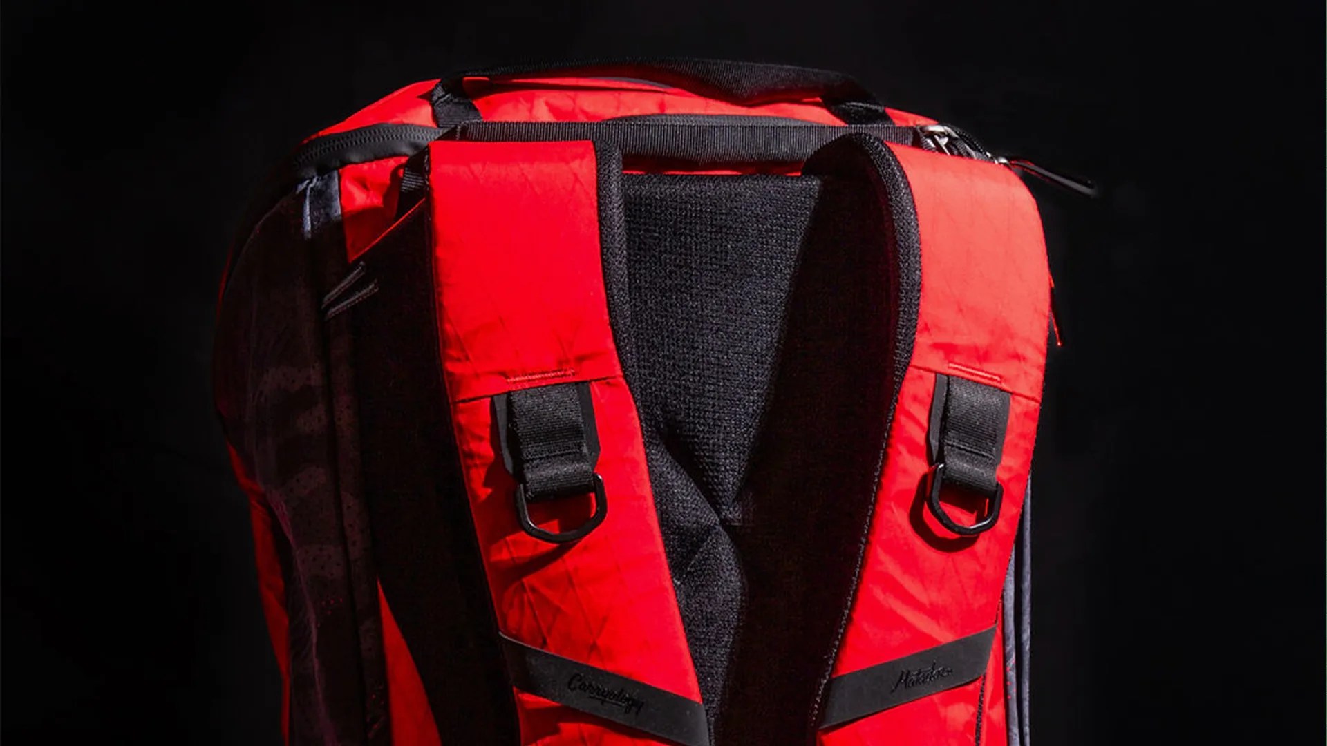 Red and black backpack straps with black D-ring attachments and padded back panel.