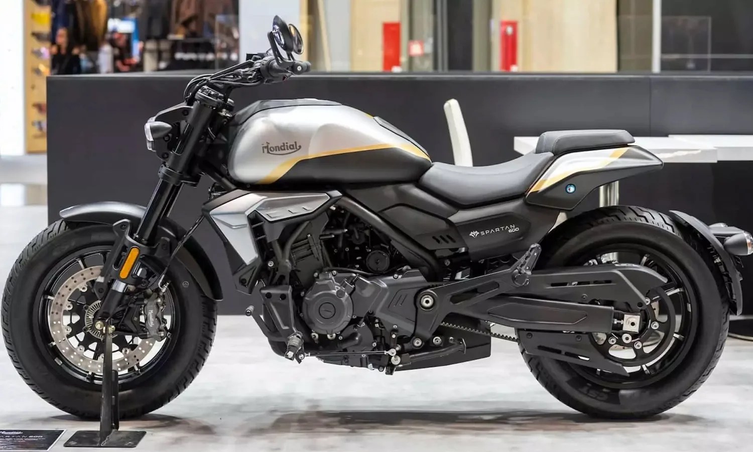 Silver and black Mondial Spartan 600 motorcycle with gold accents displayed indoors.