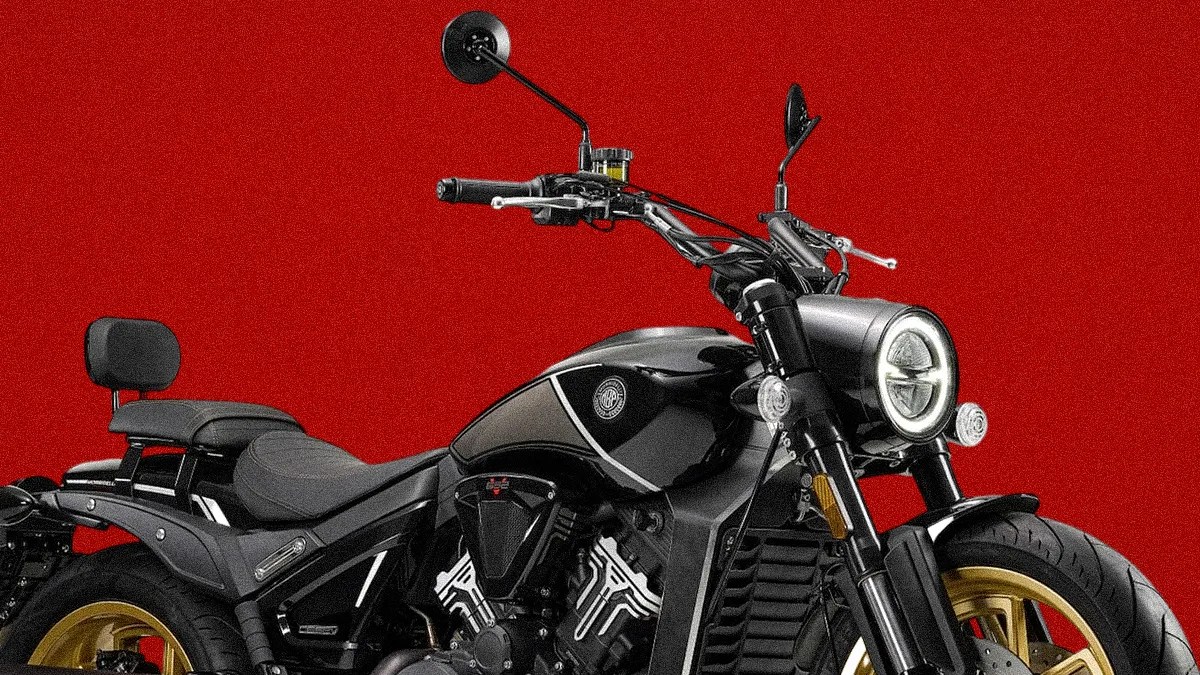 Black motorcycle with gold rims and round LED headlight against a red background.