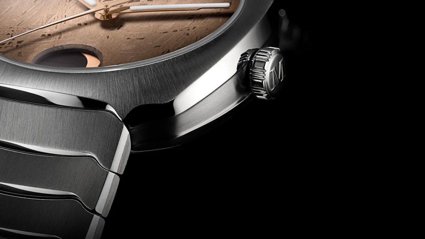 Close-up of a stainless steel watch case and crown with a textured brown dial and white hands.