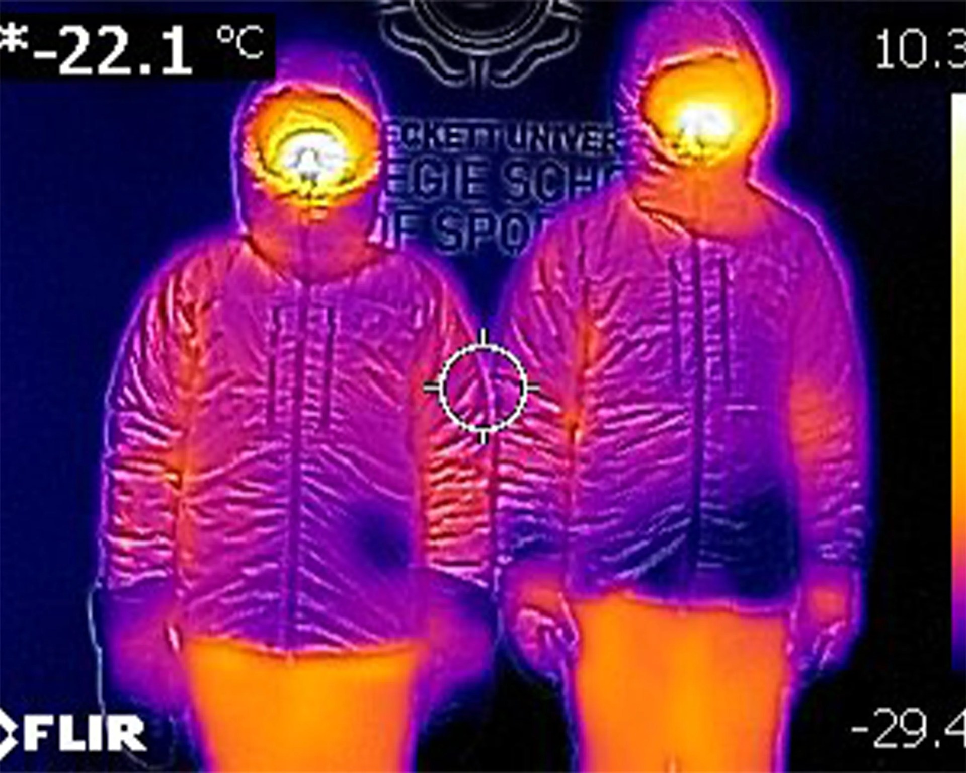 Thermal image showing two people wearing hooded jackets with warm heads and legs, cooler torsos and arms.