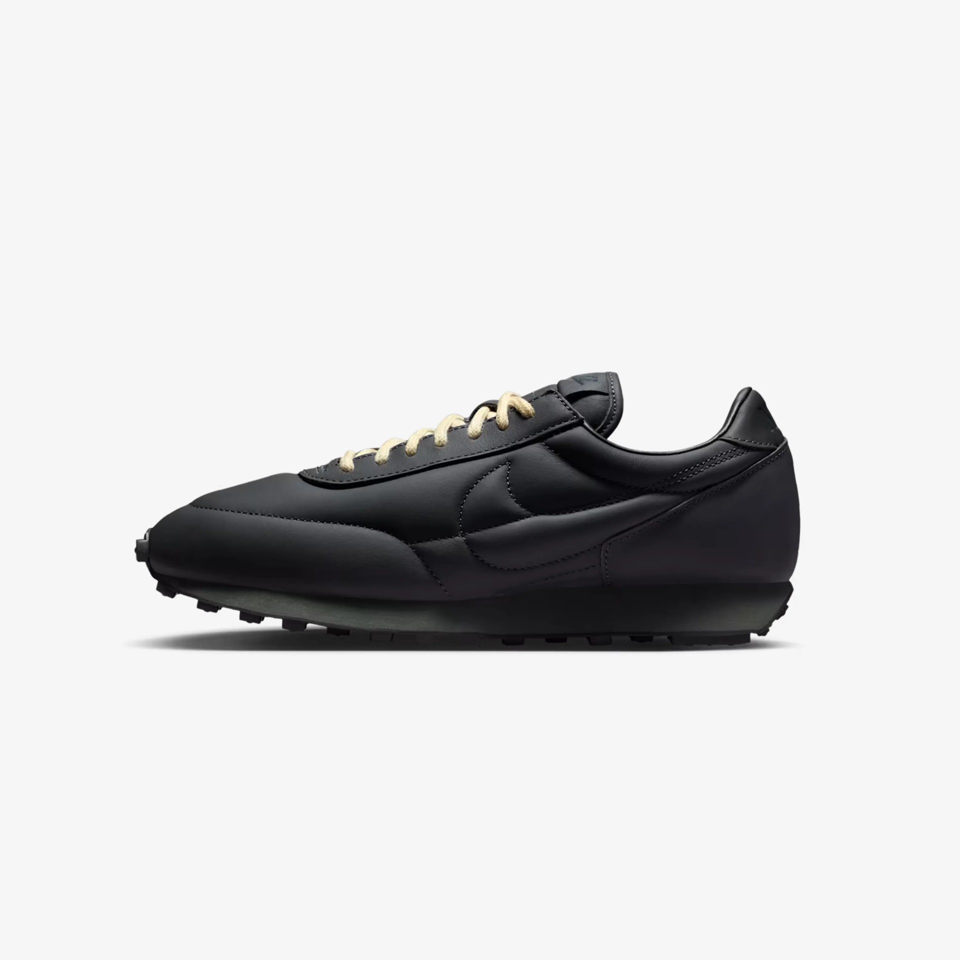 Black leather Nike sneaker with cream laces and a textured black sole, side view.