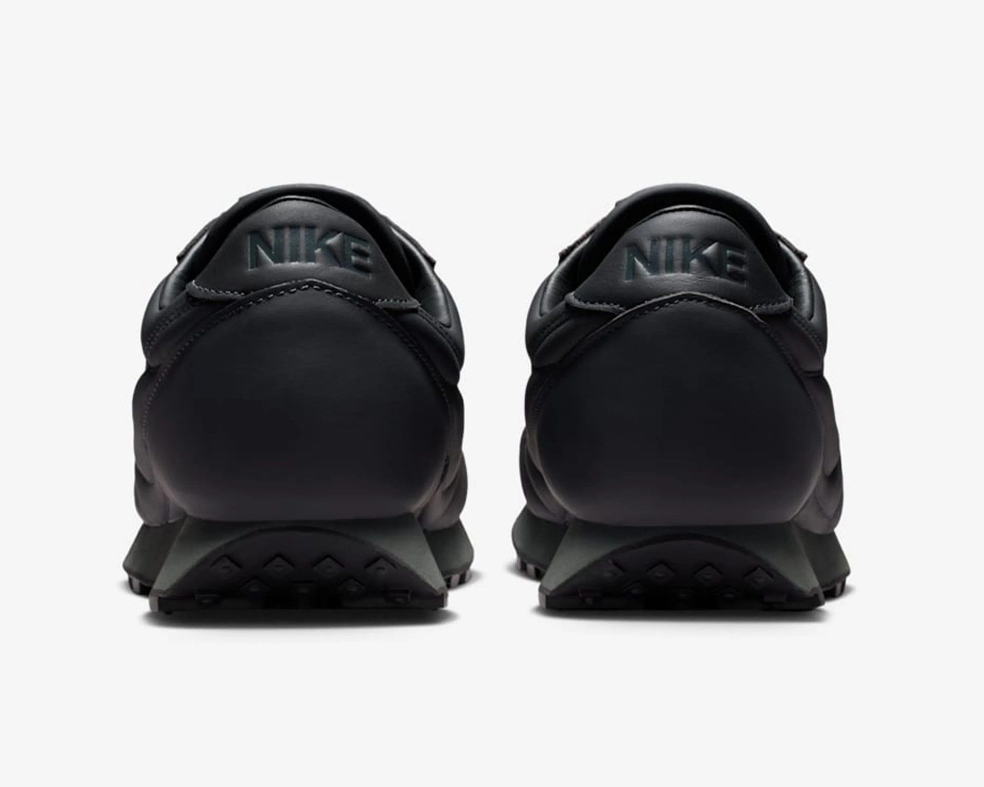 Pair of black Nike sneakers shown from the back with embossed Nike logo on the heel tab.