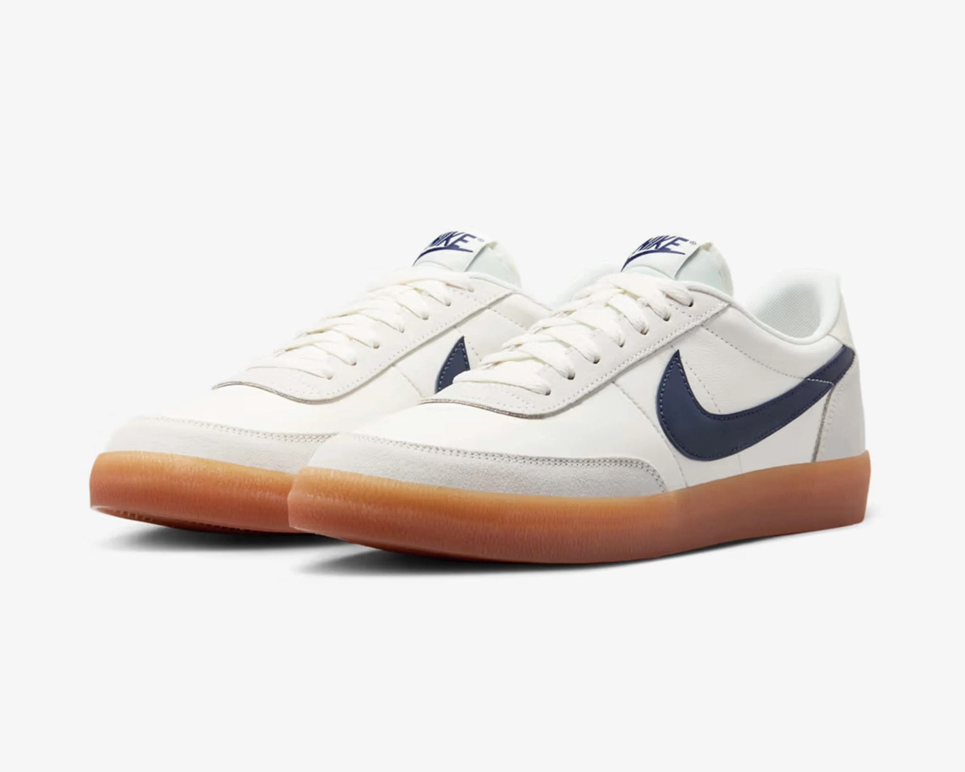 Pair of white Nike sneakers with navy blue swoosh and gum rubber soles on a white background.