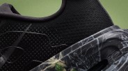 Close-up of a black knit sneaker upper with textured dots and a camo-patterned sole featuring leaf and branch designs.