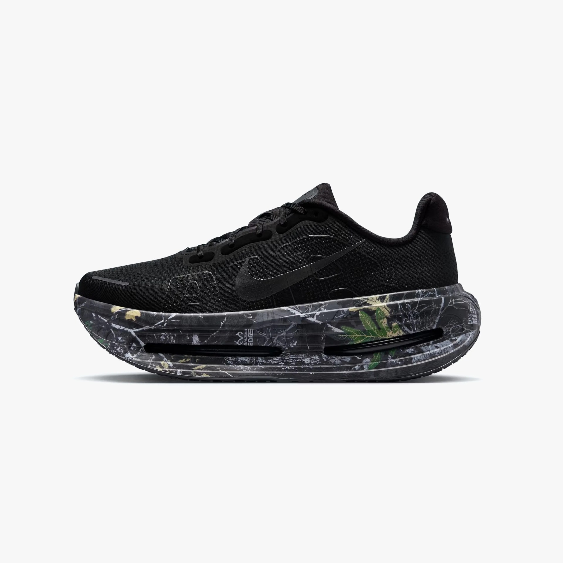 Black Nike running shoe with large black swoosh and thick marbled black and gray sole with green and yellow accents.