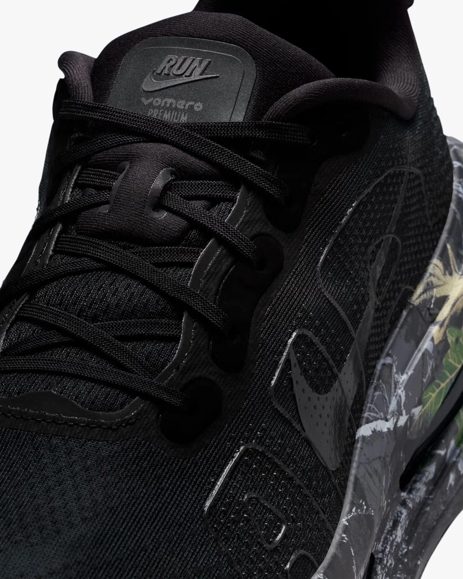 Close-up of a black Nike running shoe with black laces and a patterned midsole featuring green and beige accents.