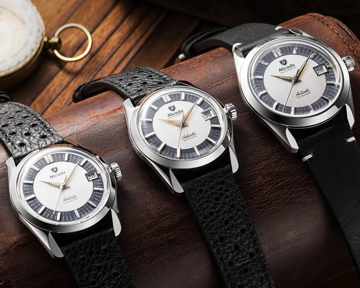 Three Nivada Antarctic Glacier wristwatches with black leather straps on a brown leather surface.