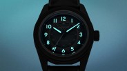 Black wristwatch with glowing blue numerals and hands on a blue gradient background.